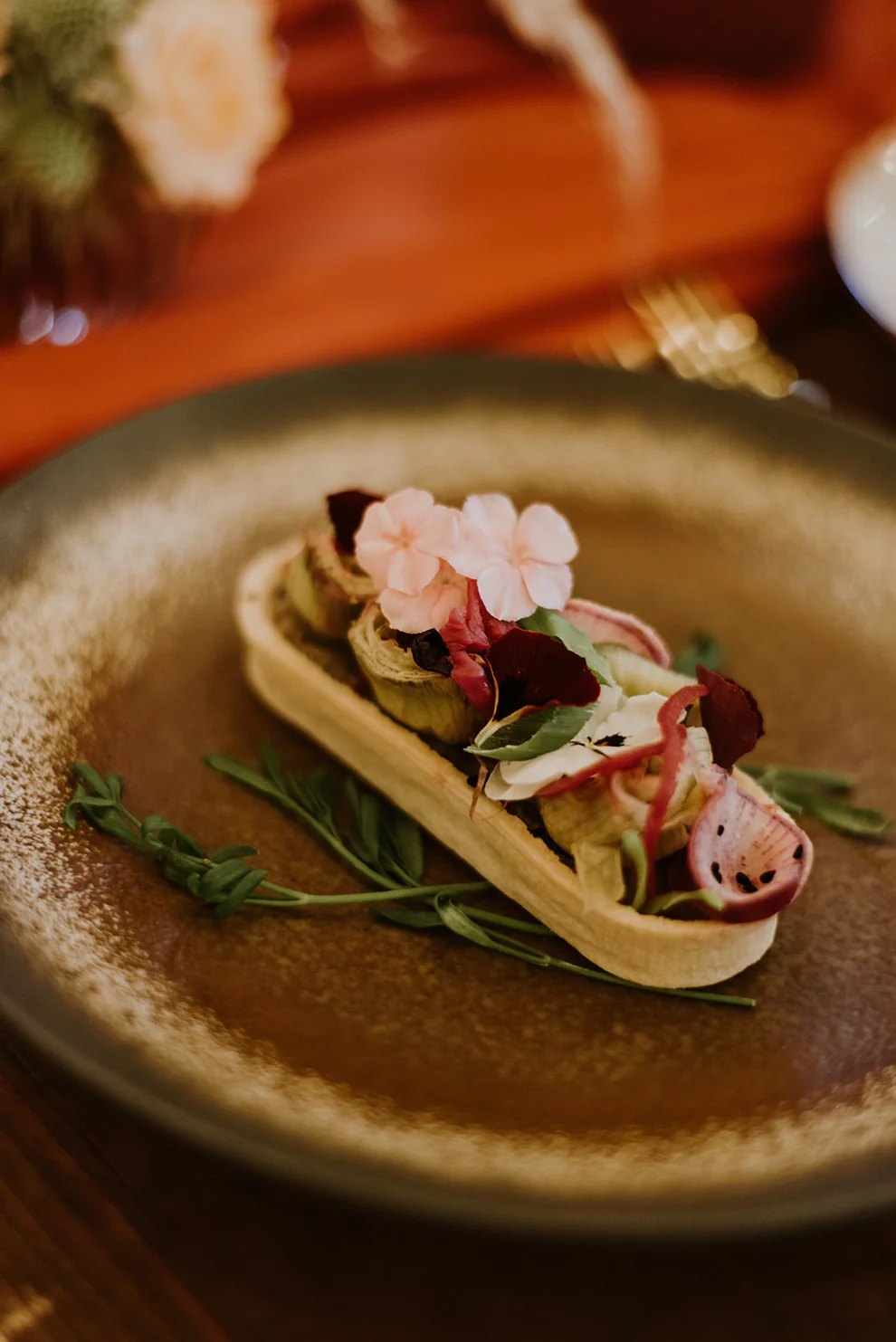 Tartelette de légumes et fleurs comestibles dressée à l'assiette
